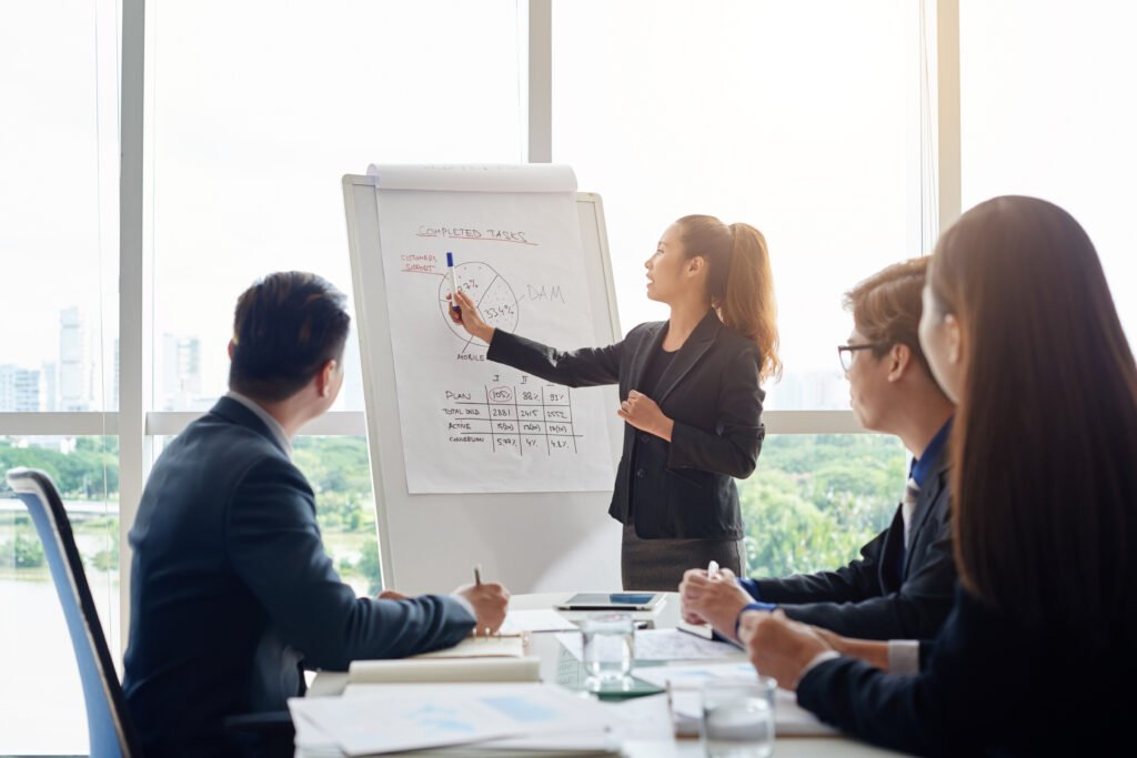 A woman holding a meeting with her colleagues, pointing at a chart to discuss key data and insights.